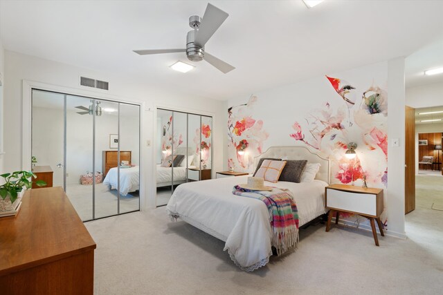 bedroom featuring multiple closets, light colored carpet, and ceiling fan