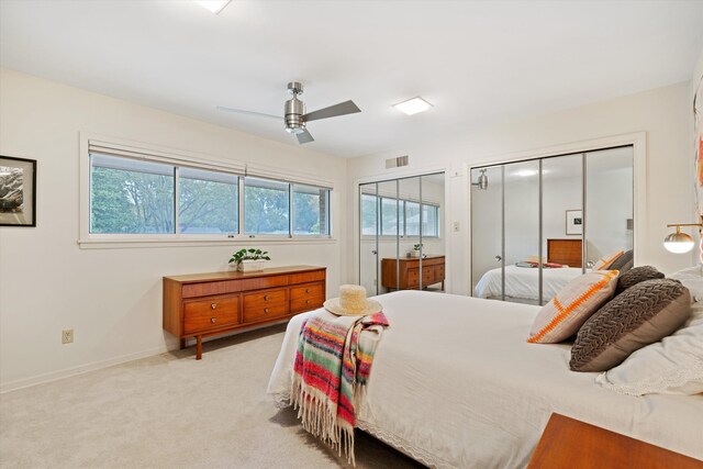 carpeted bedroom featuring multiple closets, multiple windows, and ceiling fan