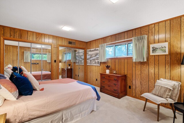 bedroom with light colored carpet, wood walls, and a closet