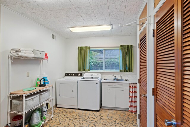 clothes washing area with light tile patterned floors, cabinets, sink, and washing machine and clothes dryer