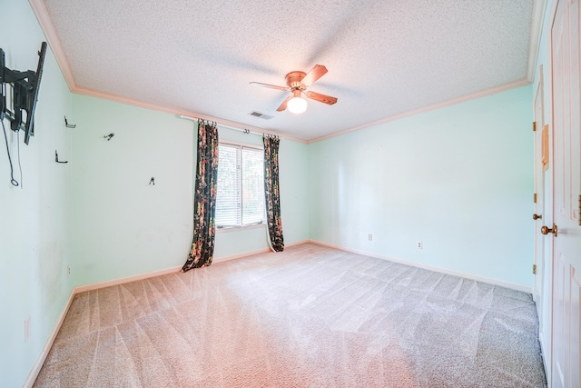 carpeted empty room featuring ceiling fan, crown molding, and a textured ceiling