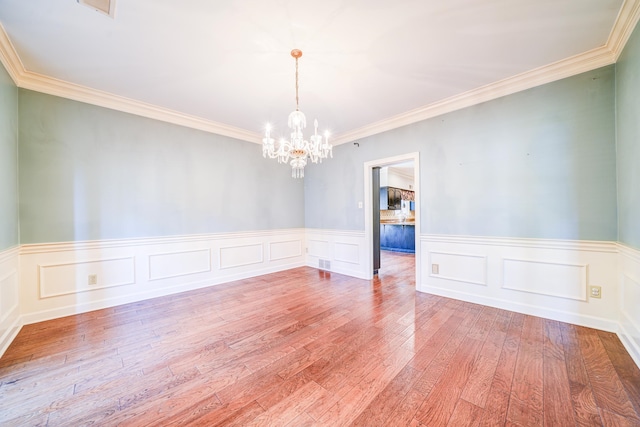 empty room featuring ornamental molding, a chandelier, and light hardwood / wood-style flooring