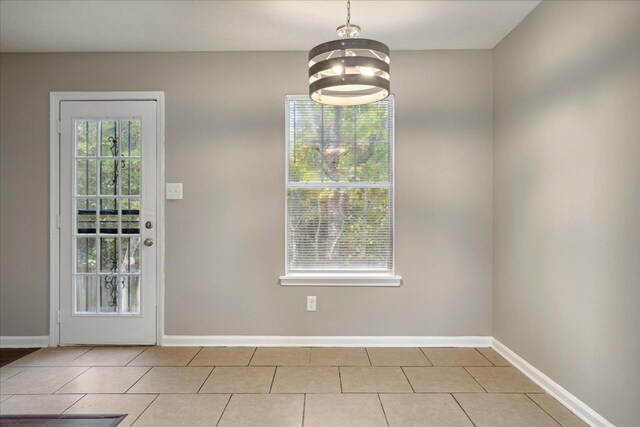 unfurnished dining area featuring light tile patterned floors and an inviting chandelier