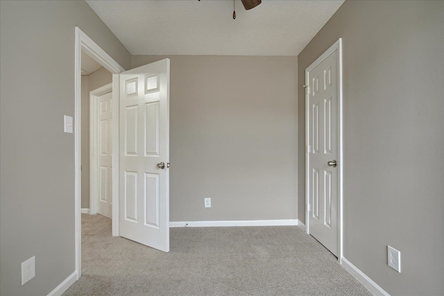 unfurnished bedroom featuring light carpet, a textured ceiling, and ceiling fan