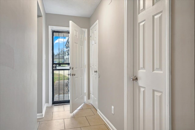 foyer entrance with a textured ceiling and light tile patterned flooring