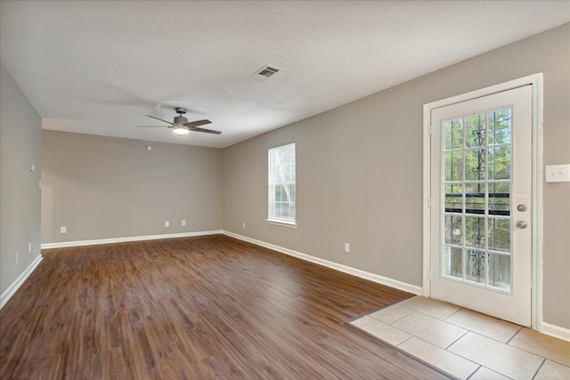 empty room featuring a textured ceiling, wood-type flooring, and ceiling fan