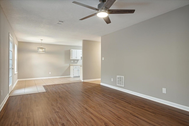 spare room with a textured ceiling, light wood-type flooring, and ceiling fan