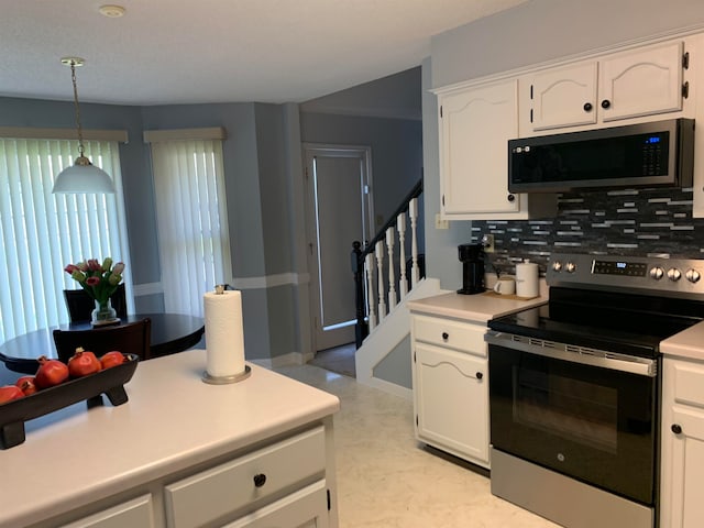 kitchen featuring white cabinets, decorative backsplash, appliances with stainless steel finishes, and decorative light fixtures