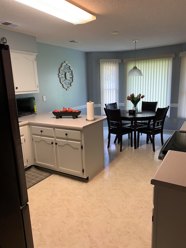 kitchen with white cabinetry, a textured ceiling, decorative light fixtures, and stainless steel fridge