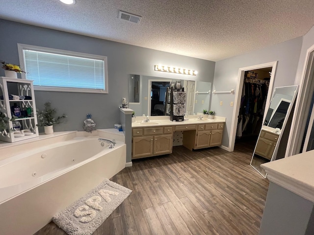 bathroom featuring a tub to relax in, vanity, a textured ceiling, and hardwood / wood-style flooring