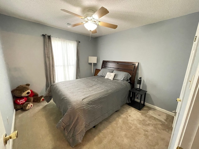 bedroom featuring a textured ceiling, light carpet, and ceiling fan