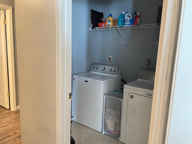 clothes washing area with light hardwood / wood-style floors and washer and clothes dryer