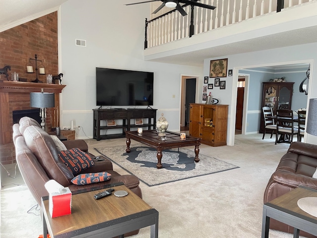 living room featuring carpet floors, ornamental molding, ceiling fan, a fireplace, and a high ceiling