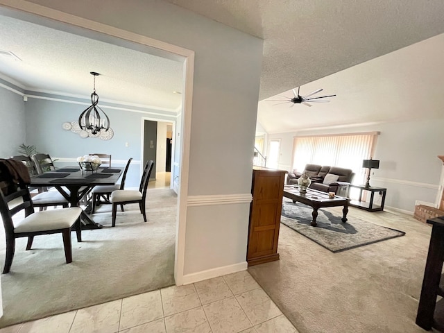 dining area with ceiling fan with notable chandelier, a textured ceiling, crown molding, light colored carpet, and vaulted ceiling