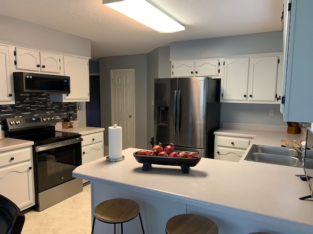 kitchen featuring white cabinetry, appliances with stainless steel finishes, sink, and a kitchen bar