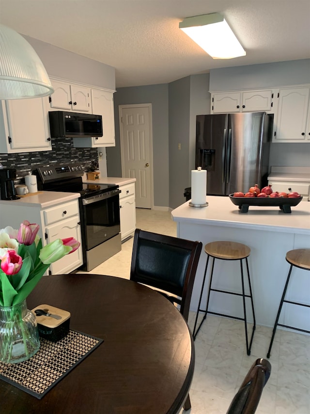 kitchen with stainless steel appliances, a breakfast bar area, white cabinets, and backsplash