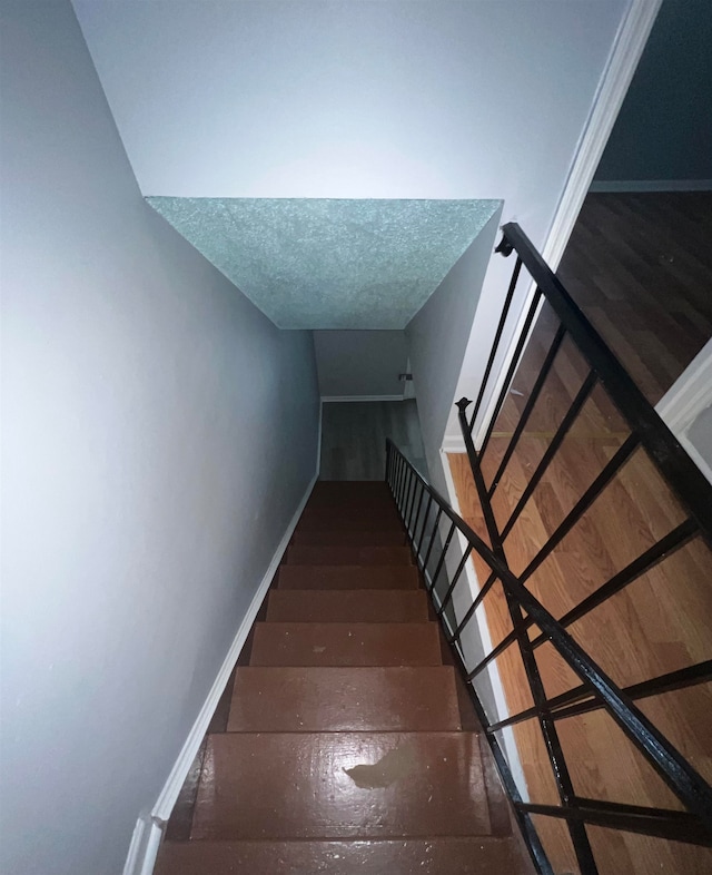 stairs with hardwood / wood-style floors and a textured ceiling