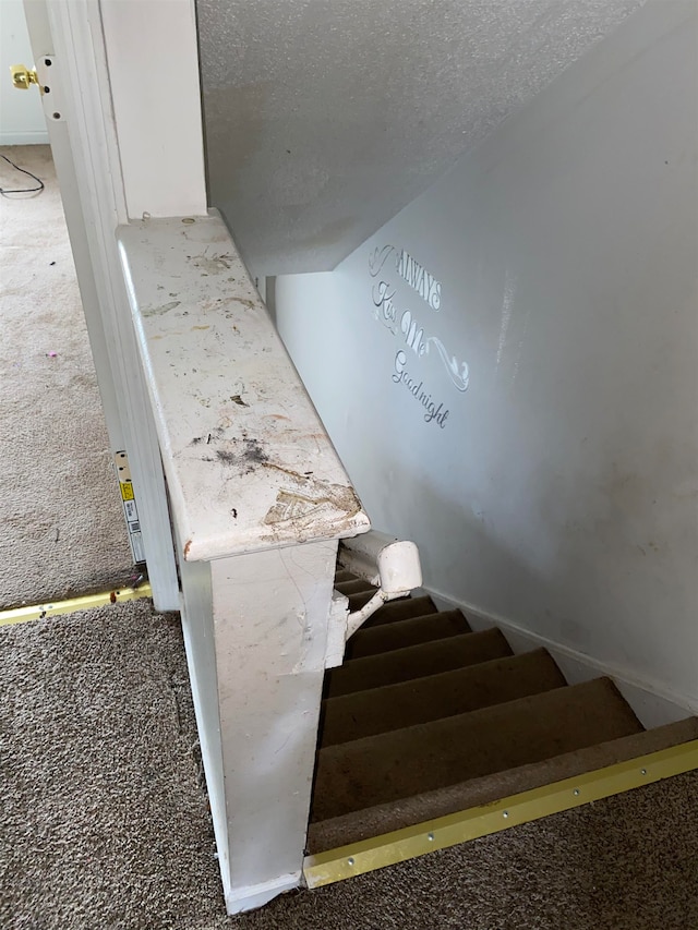 staircase featuring a textured ceiling and carpet flooring