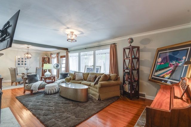 living room featuring wood-type flooring, ornamental molding, and a chandelier