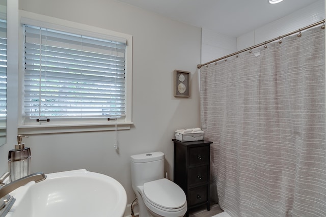 bathroom featuring sink, curtained shower, and toilet