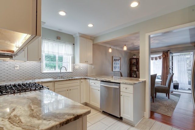 kitchen with light stone counters, light hardwood / wood-style flooring, ornamental molding, sink, and stainless steel appliances