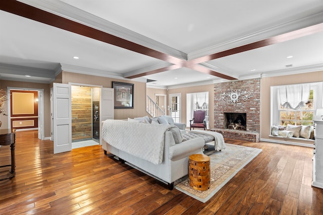 living room with beamed ceiling, ornamental molding, a brick fireplace, and hardwood / wood-style flooring