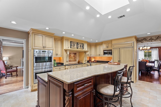 kitchen with a spacious island, dark stone countertops, light hardwood / wood-style floors, lofted ceiling with skylight, and stainless steel appliances