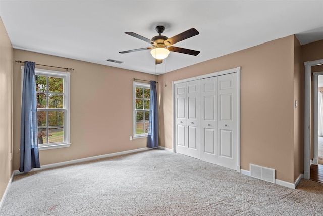 unfurnished bedroom with a closet, light colored carpet, and ceiling fan