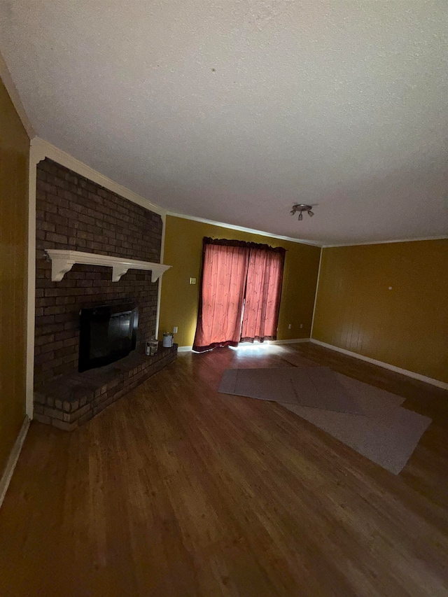 unfurnished living room with crown molding, hardwood / wood-style floors, a textured ceiling, and a brick fireplace