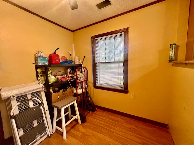 interior space featuring hardwood / wood-style floors, heating unit, ceiling fan, a textured ceiling, and ornamental molding