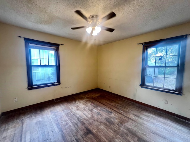 spare room featuring a wealth of natural light, a textured ceiling, dark hardwood / wood-style floors, and ceiling fan