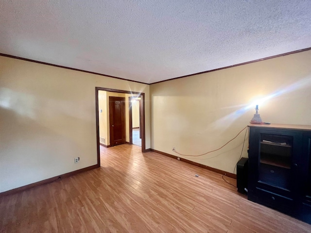 spare room featuring a textured ceiling, light hardwood / wood-style flooring, and ornamental molding