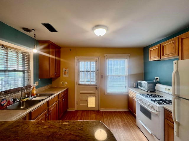 kitchen with light hardwood / wood-style floors, decorative light fixtures, a wealth of natural light, and white appliances