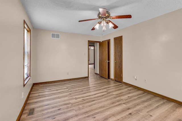 spare room with ceiling fan, a textured ceiling, and light wood-type flooring