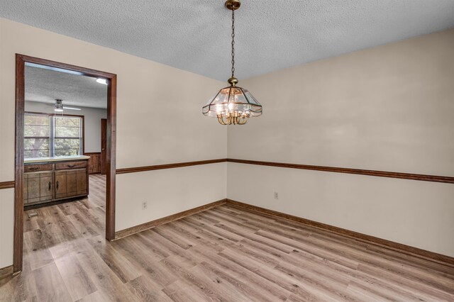 9430 Monasco Rd, Millington, TN 38053 - empty room with a textured ceiling, light wood-type flooring, a chandelier, and baseboards