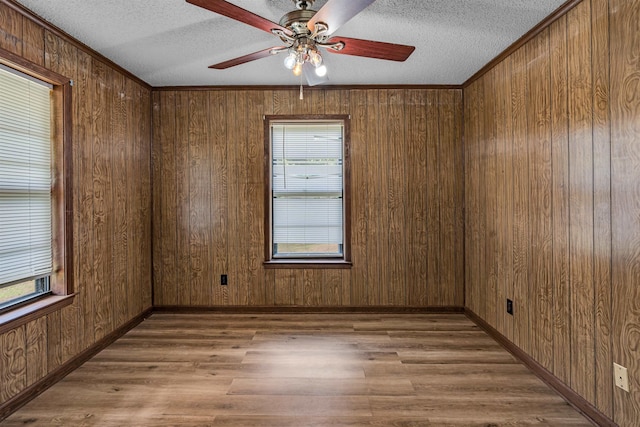 empty room featuring wood walls, a textured ceiling, wood-type flooring, and ceiling fan