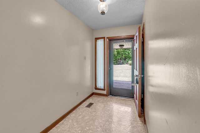 doorway to outside featuring a textured ceiling