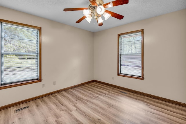 spare room featuring a textured ceiling, light wood-type flooring, and a wealth of natural light