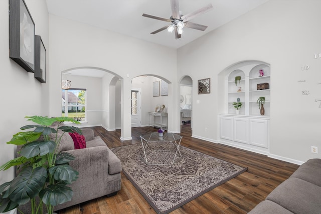 living room with dark hardwood / wood-style flooring, built in features, and ceiling fan