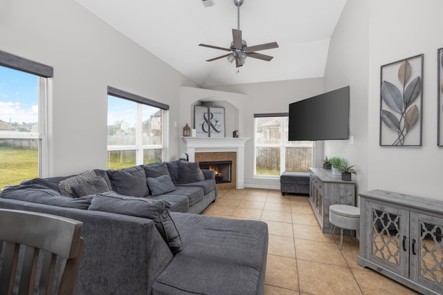 tiled living room with high vaulted ceiling, ceiling fan, a healthy amount of sunlight, and a tile fireplace