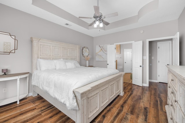 bedroom featuring a raised ceiling, ceiling fan, and dark hardwood / wood-style flooring