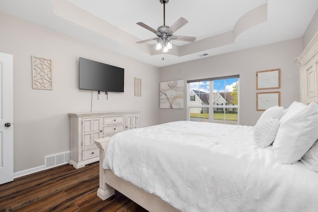 bedroom featuring a tray ceiling, ceiling fan, and dark hardwood / wood-style flooring