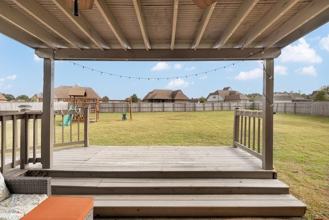 wooden deck featuring a playground and a lawn