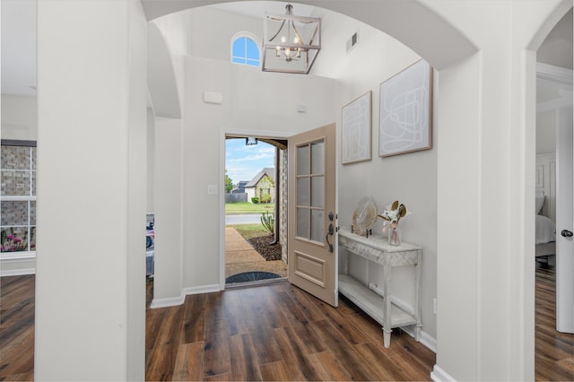 foyer entrance with a towering ceiling, dark hardwood / wood-style flooring, and a notable chandelier