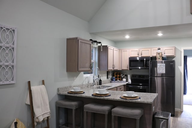 kitchen with kitchen peninsula, stainless steel appliances, lofted ceiling, and sink