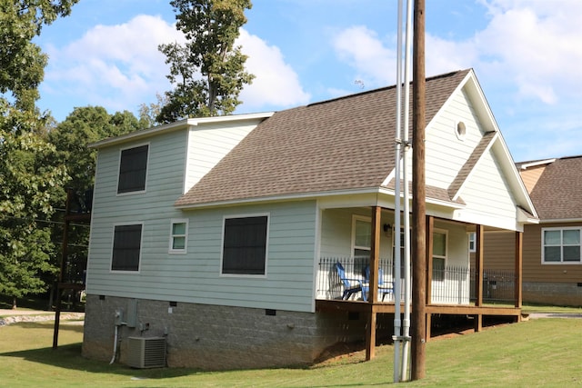 rear view of house with central air condition unit and a lawn