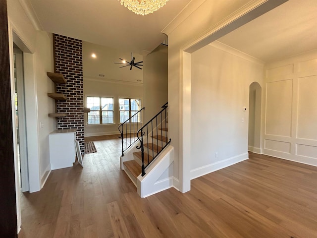 interior space with hardwood / wood-style floors, ceiling fan with notable chandelier, and ornamental molding