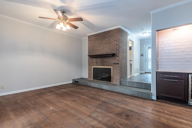 unfurnished living room featuring a tile fireplace, crown molding, ceiling fan, and dark wood-type flooring