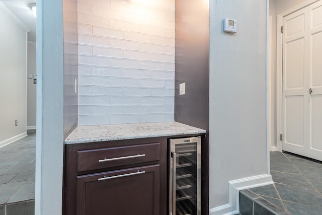 bar featuring wine cooler, crown molding, dark brown cabinets, and light stone counters