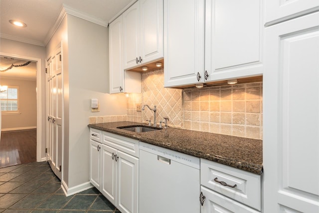 kitchen featuring white cabinets, ornamental molding, dark stone counters, sink, and dishwasher